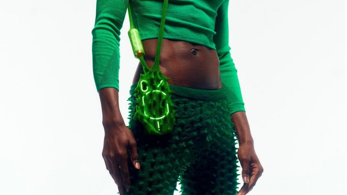 Женщина с зелеными наушниками Ear stick TWS и ярким костюмом