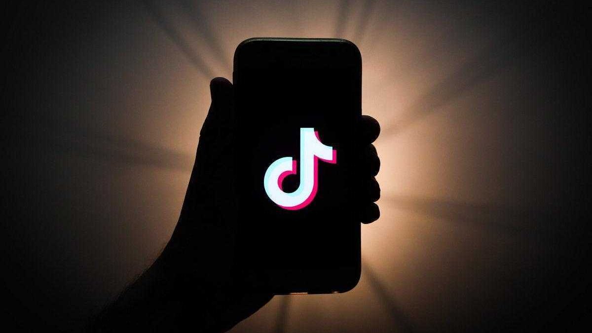 Смартфон с логотипом TikTok на экране в темной обстановке