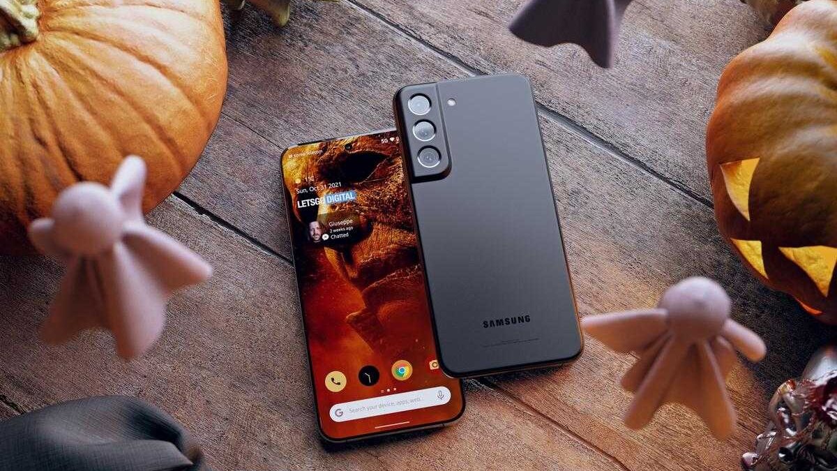 Смартфон Samsung Galaxy S23 на деревянном столе с тыквами и скелетным декором