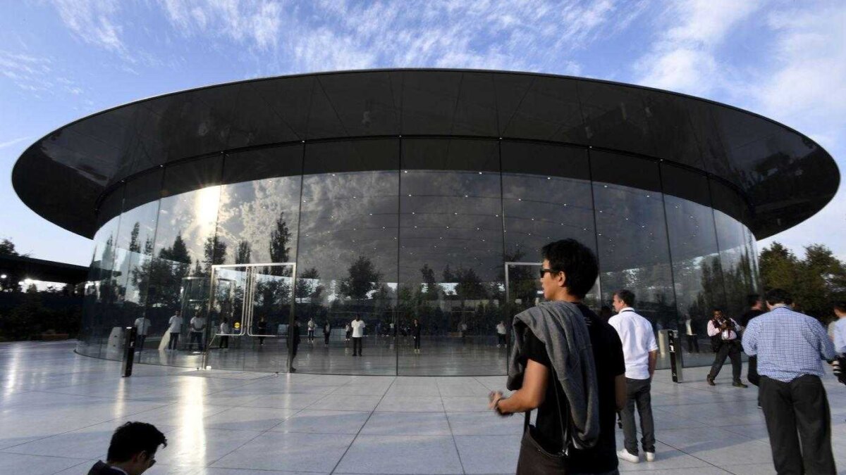 Группа людей возле круглого стеклянного здания с Apple гарнитурой смешанной реальности на мероприятии