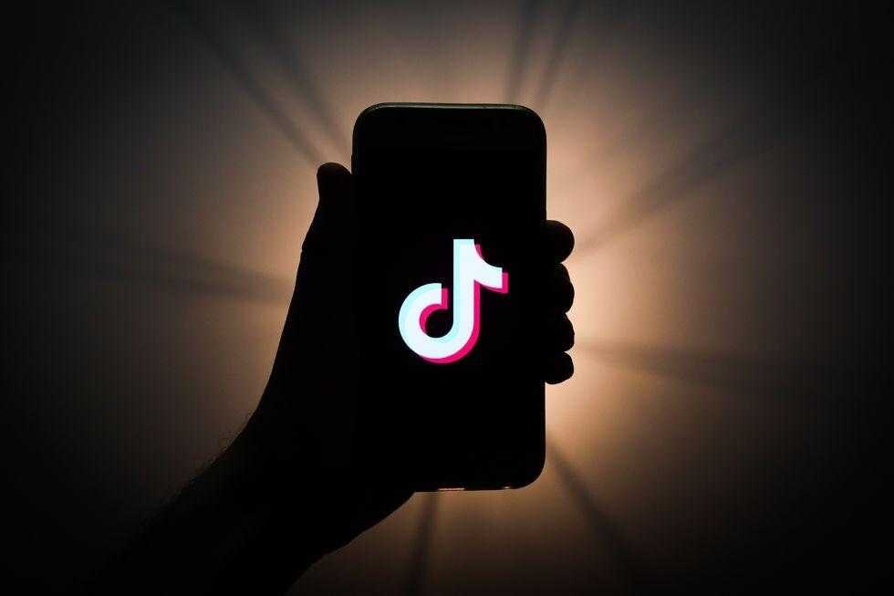 Смартфон с логотипом TikTok на экране в темной обстановке