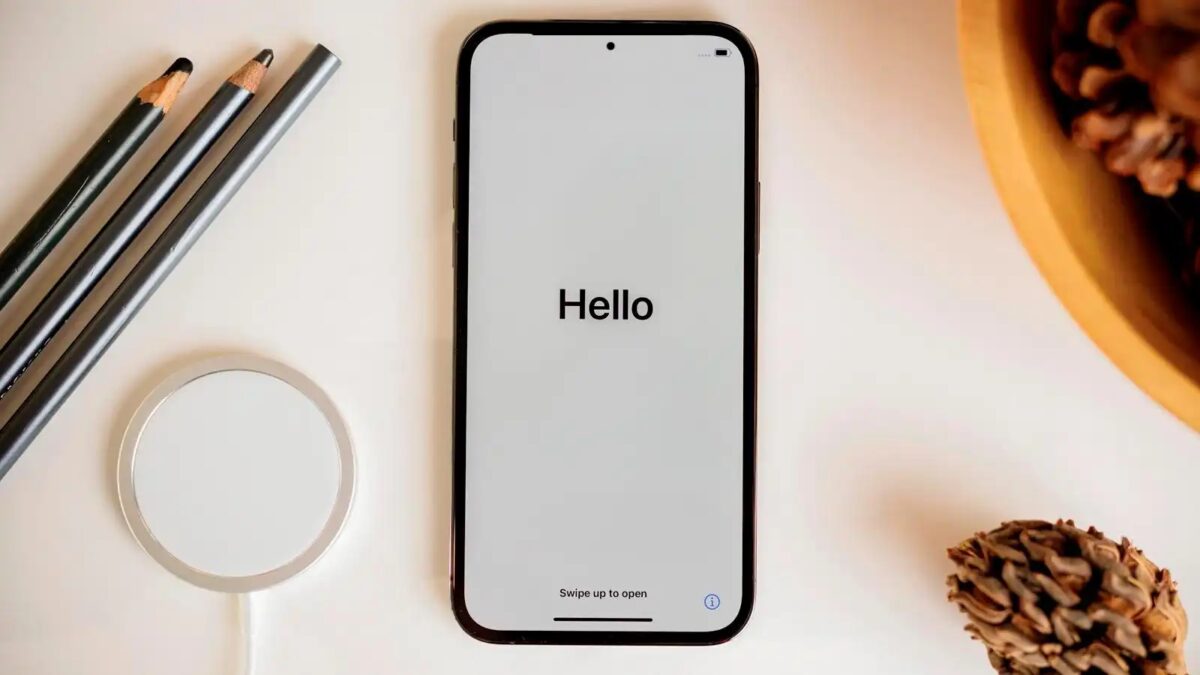 Смартфон iPhone с экраном «Hello» на бежевом фоне