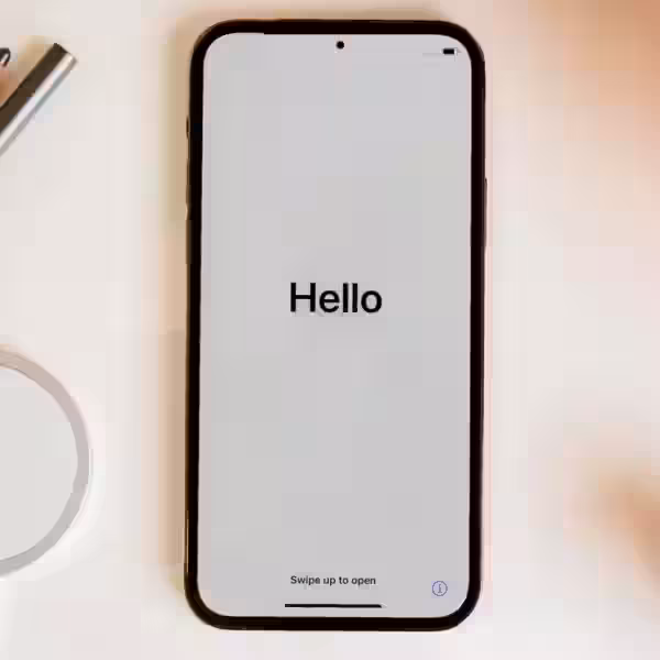 Смартфон iPhone с экраном «Hello» на бежевом фоне