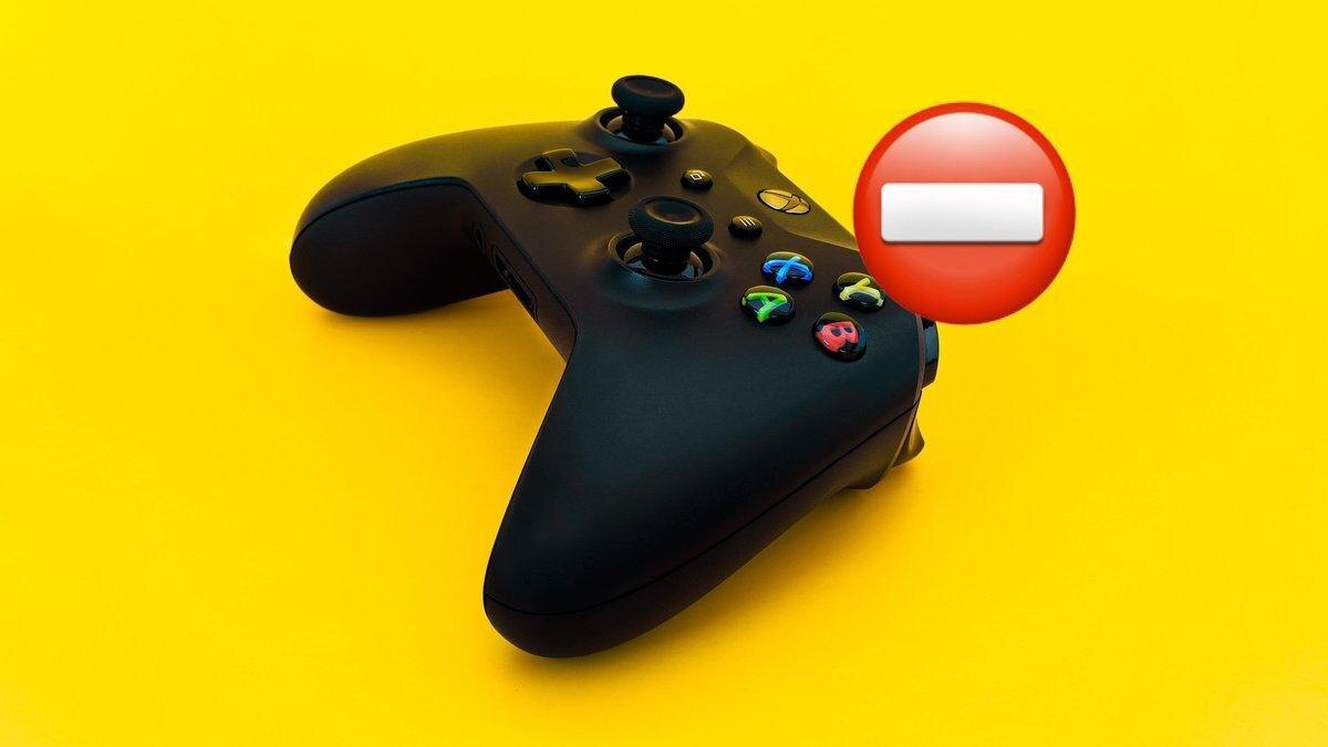 Черный контроллер Xbox на желтом фоне и знак запрета