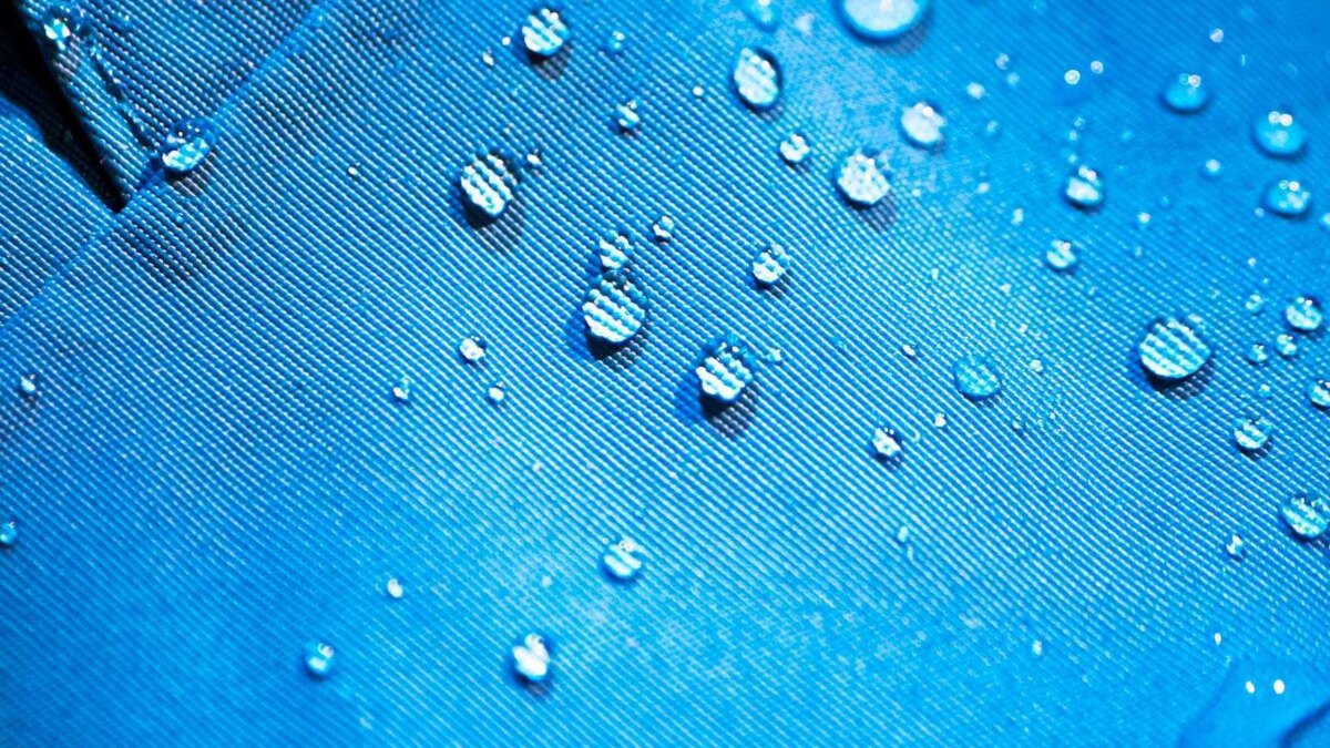 Мелкие капли воды на водоотталкивающей поверхности ткани