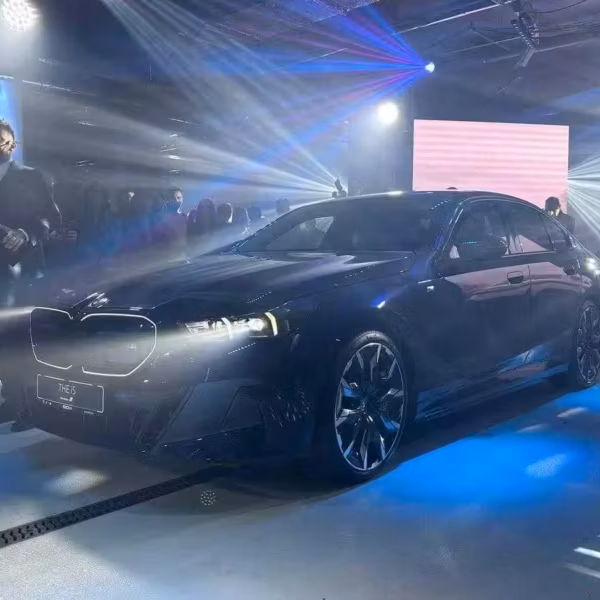 Черная новая BMW G60 в стиле шоурума с ярким освещением и присутствием людей