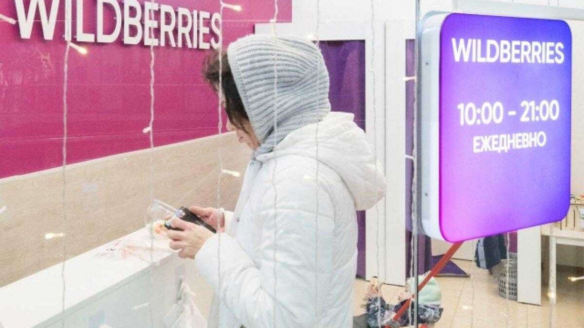Человек в зимней одежде использует телефон у стойки Вайлдберриз