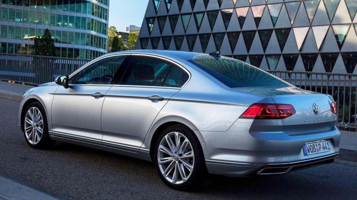 Серебристый Volkswagen Passat с четырьмя дверьми со стороны задней части в городской среде