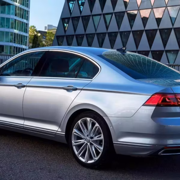 Серебристый Volkswagen Passat с четырьмя дверьми со стороны задней части в городской среде