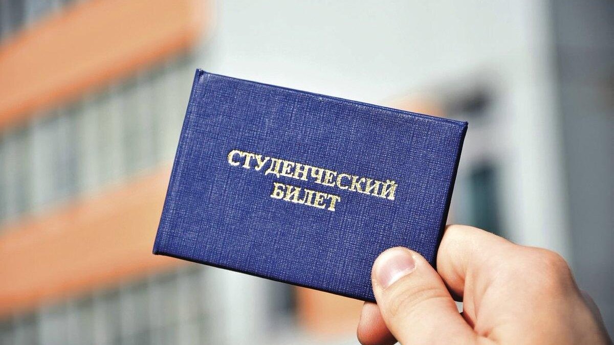 Рука держит медный студенческий билет на фоне здания, электронная версия