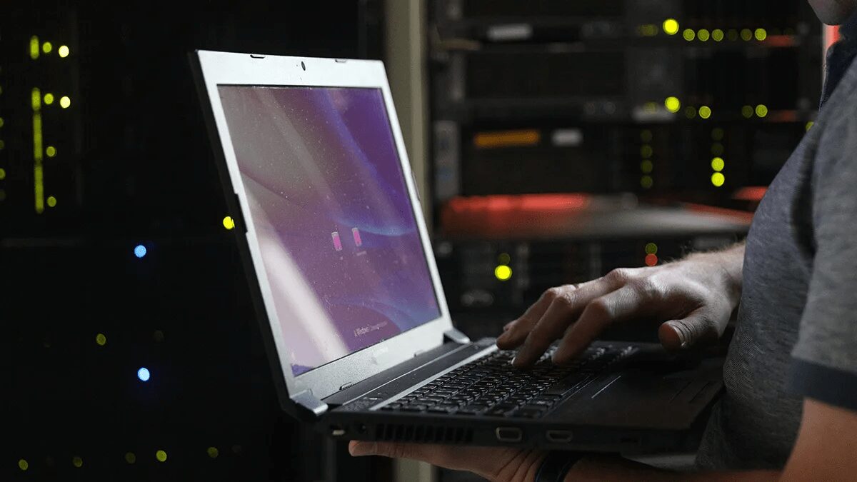 Ноутбук в дата-центре показывает работу Angie PRO на фоне серверного оборудования