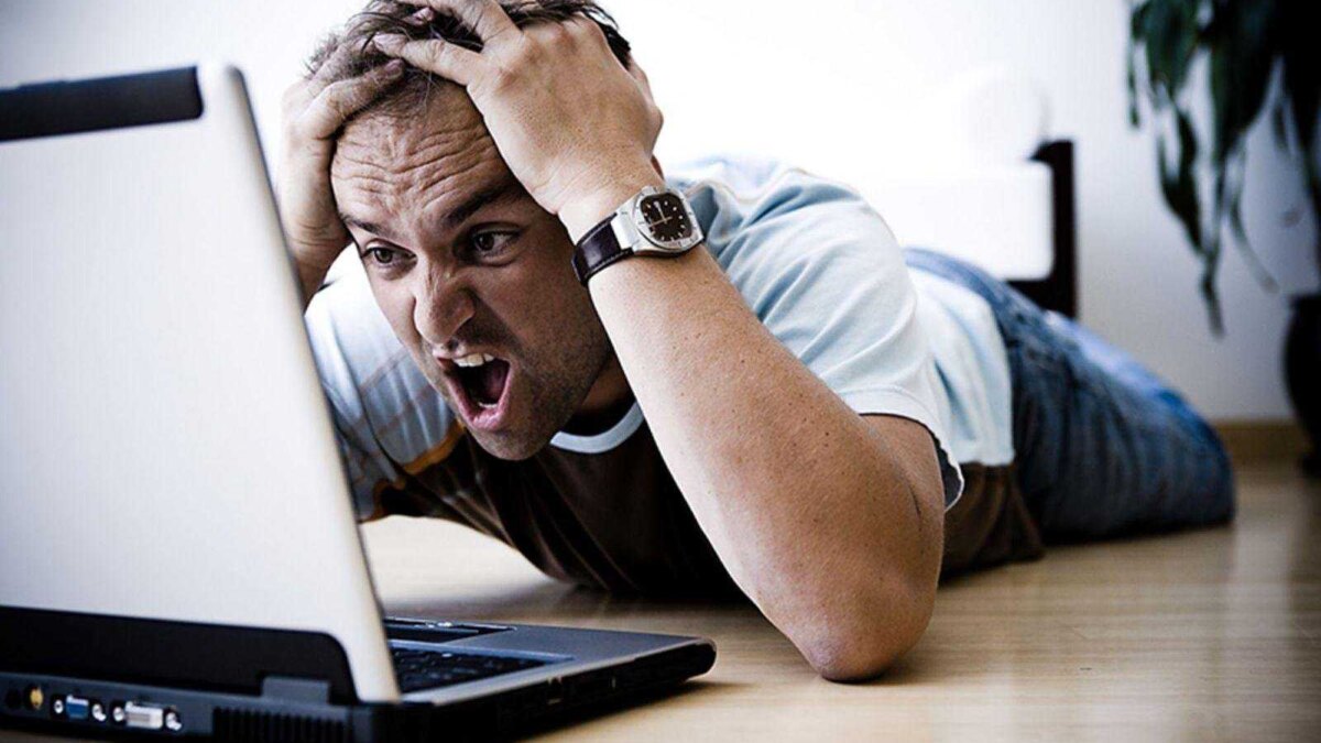Мужчина в офисе перед ноутбуком во время сбоя, эмоции на фоне поломки