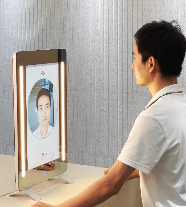 Мужчина сидит перед умным зеркалом Anura MagicMirror тестируя распознавание лица