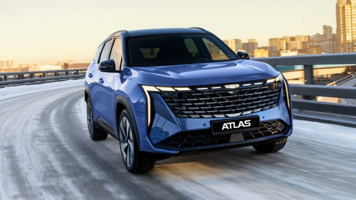 Синий кроссовер Geely Atlas на зимней дороге в городе, Россия