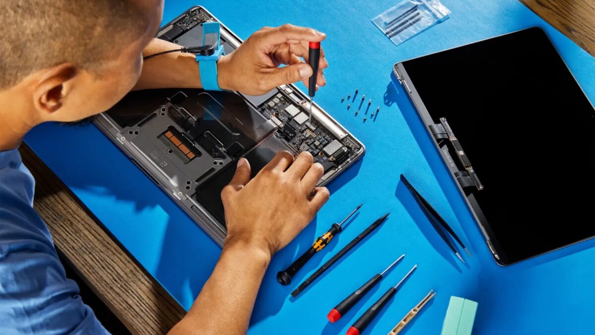 Работник ремонтирует внутренние компоненты MacBook Pro на синем рабочем столе