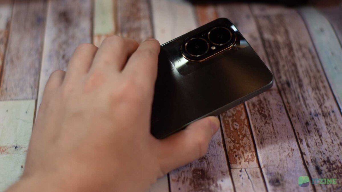 Рука держит смартфон realme C67 на деревянной поверхности
