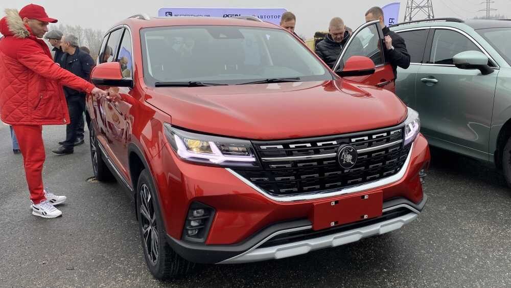 Красный кроссовер Forthing T5 на выставке с людьми рядом