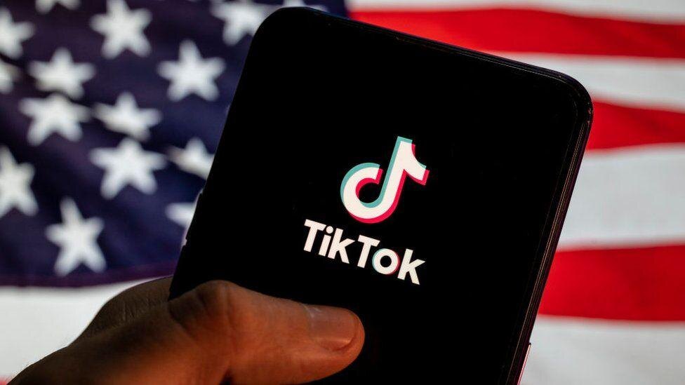 Смартфон с логотипом TikTok на фоне американского флага