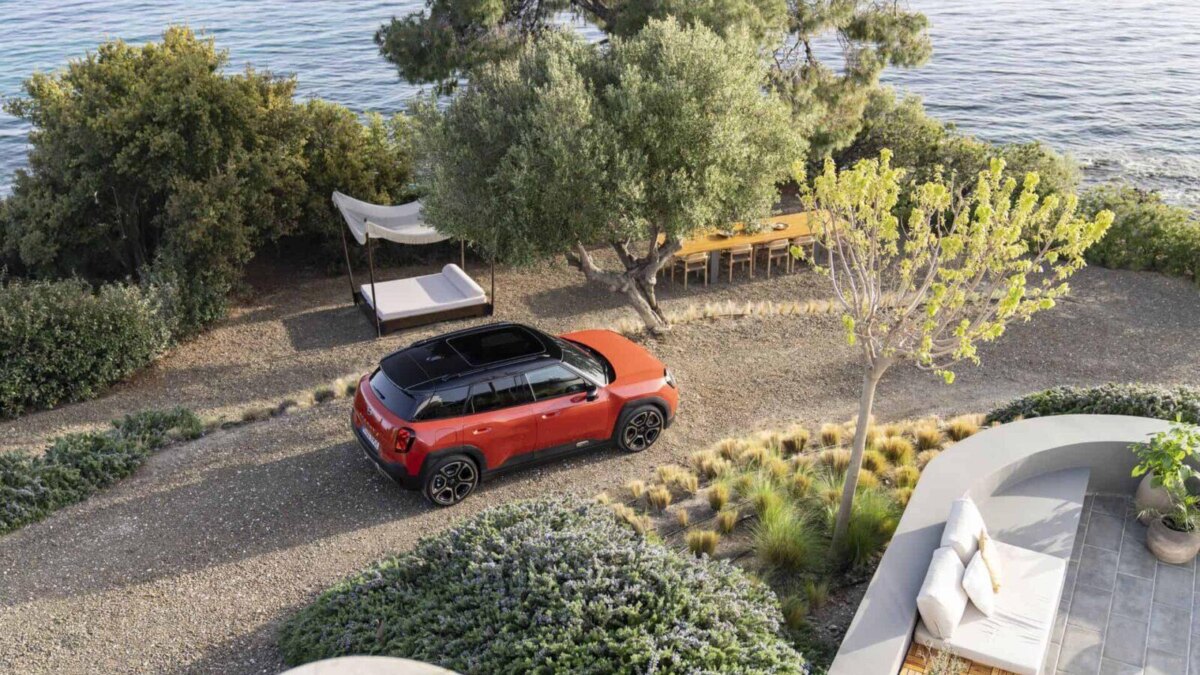 Красный электромобиль MINI Aceman на грунтовой дороге у моря