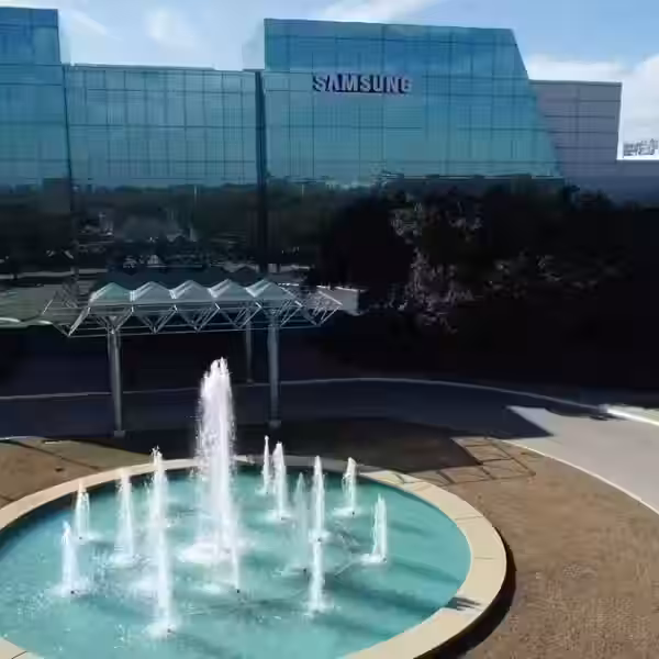 Современное здание Samsung с водным фонтаном на территории и отражением в стекле