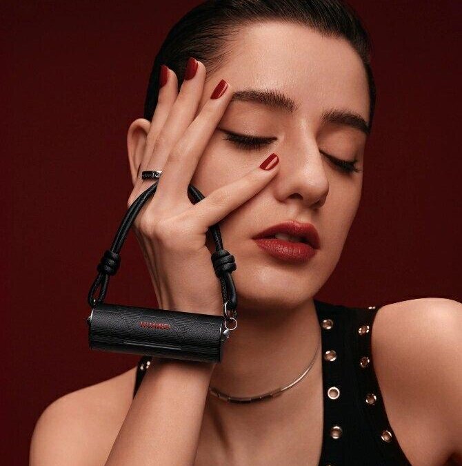 Женщина держит черные наушники HUAWEI FreeBuds Lipstick 2 у лица