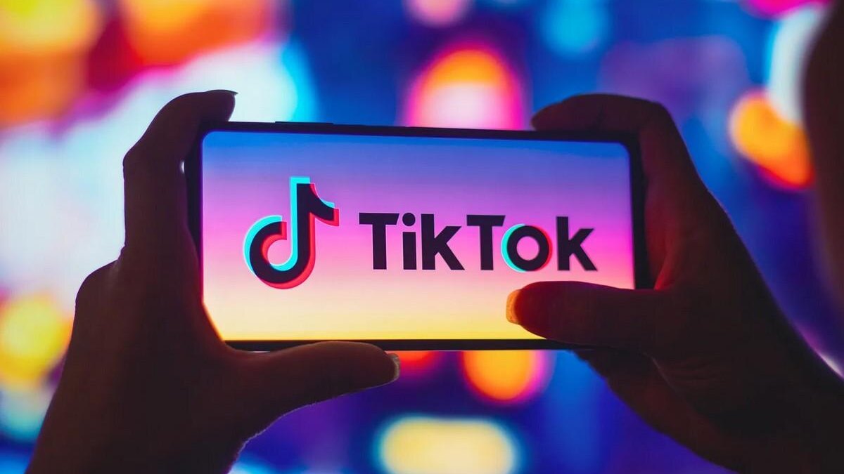 Рука держит смартфон с логотипом TikTok на экране