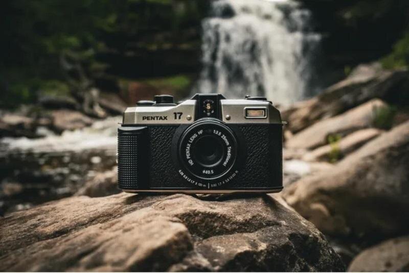 Пленочная камера Pentax 17 на камне у реки