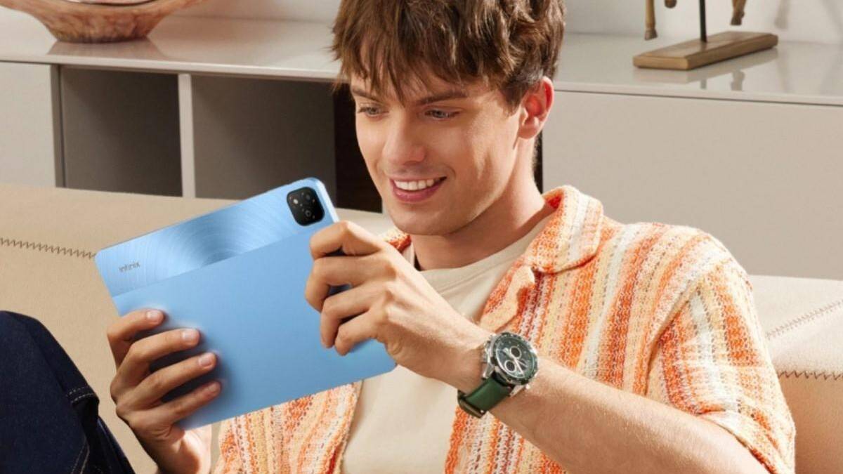Представлен 11-дюймовый планшет Infinix Xpad 5 Парень держит синий планшет Infinix Xpad в руке