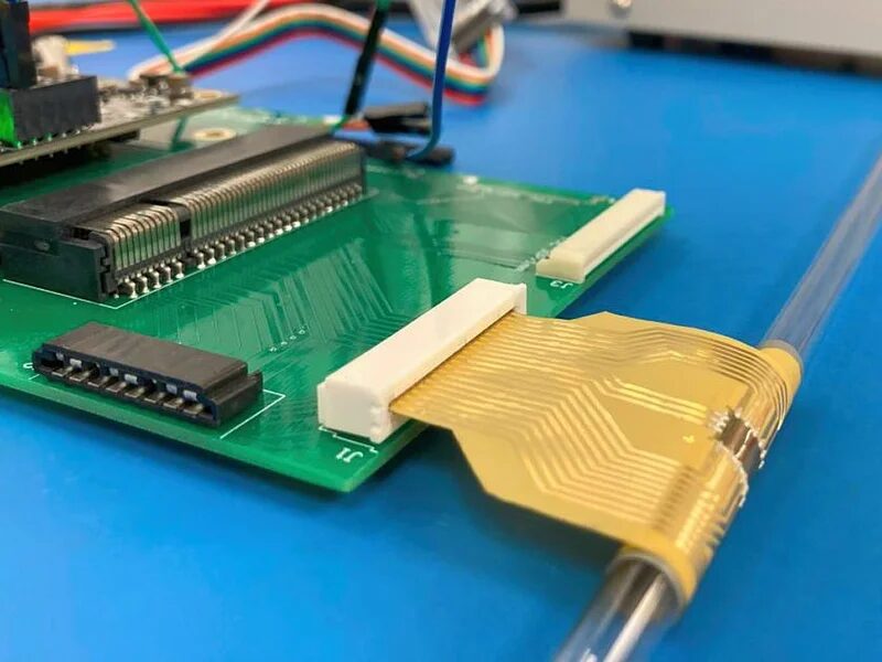 Создан первый в мире гибкий микропроцессор без кремния 5 a green circuit board attached to a flexible golden chip wrapped around a thin tube.jpg