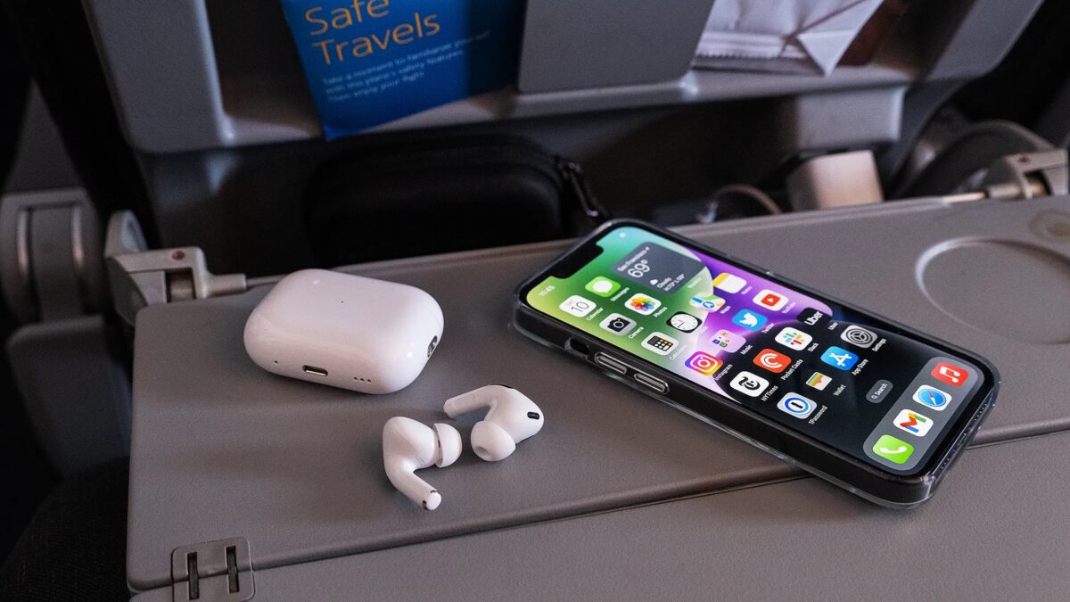 На фото беспроводные наушники AirPods и iPhone на столе внутри самолета