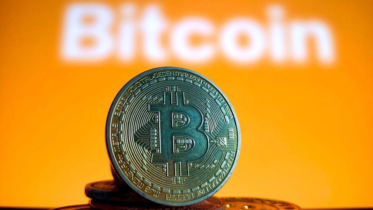 Биткоин-коин на оранжевом фоне с надписью Bitcoin, иллюстрация криптовалюты