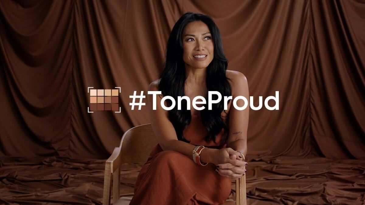 Кампания Tecno #ToneProud: женщина сидит перед фоном с логотипом #ToneProud