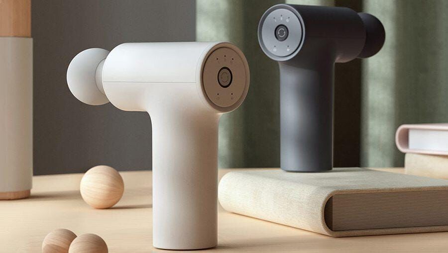 Два массажных устройства в белом и черном цвете, расположенные на деревянной поверхности