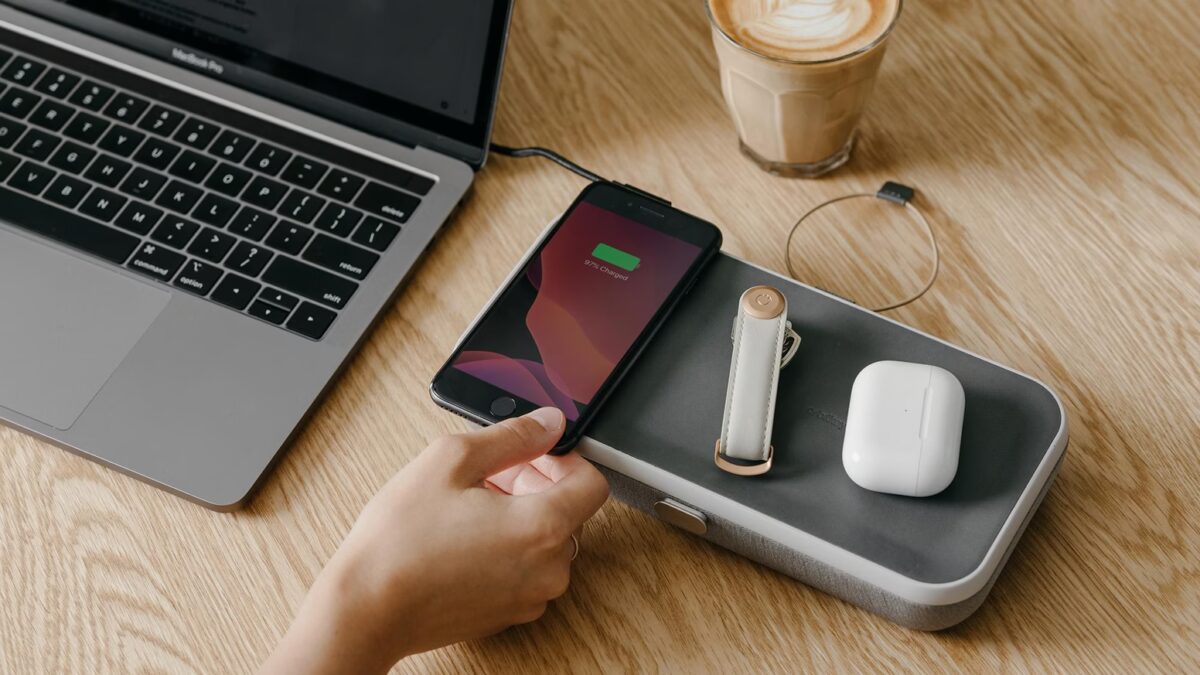 Беспроводные зарядные устройства, iPhone и наушники на деревянном столе