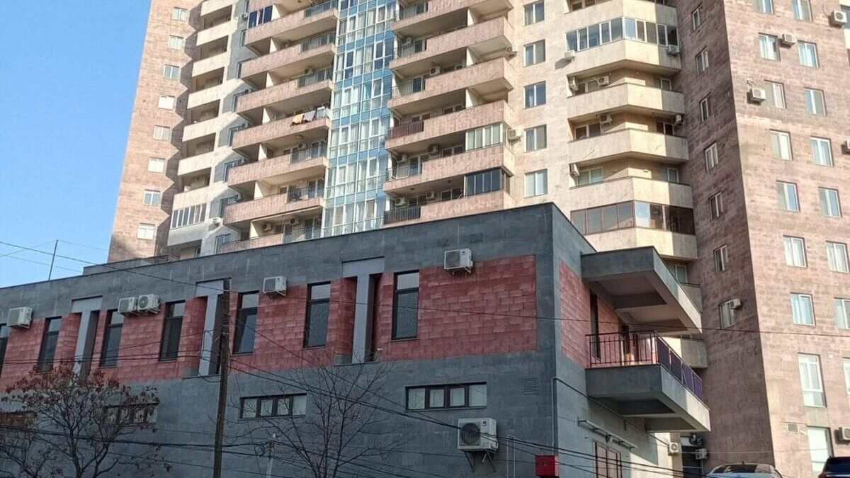 Многоэтажное жилое здание с балконами и машинами на парковке