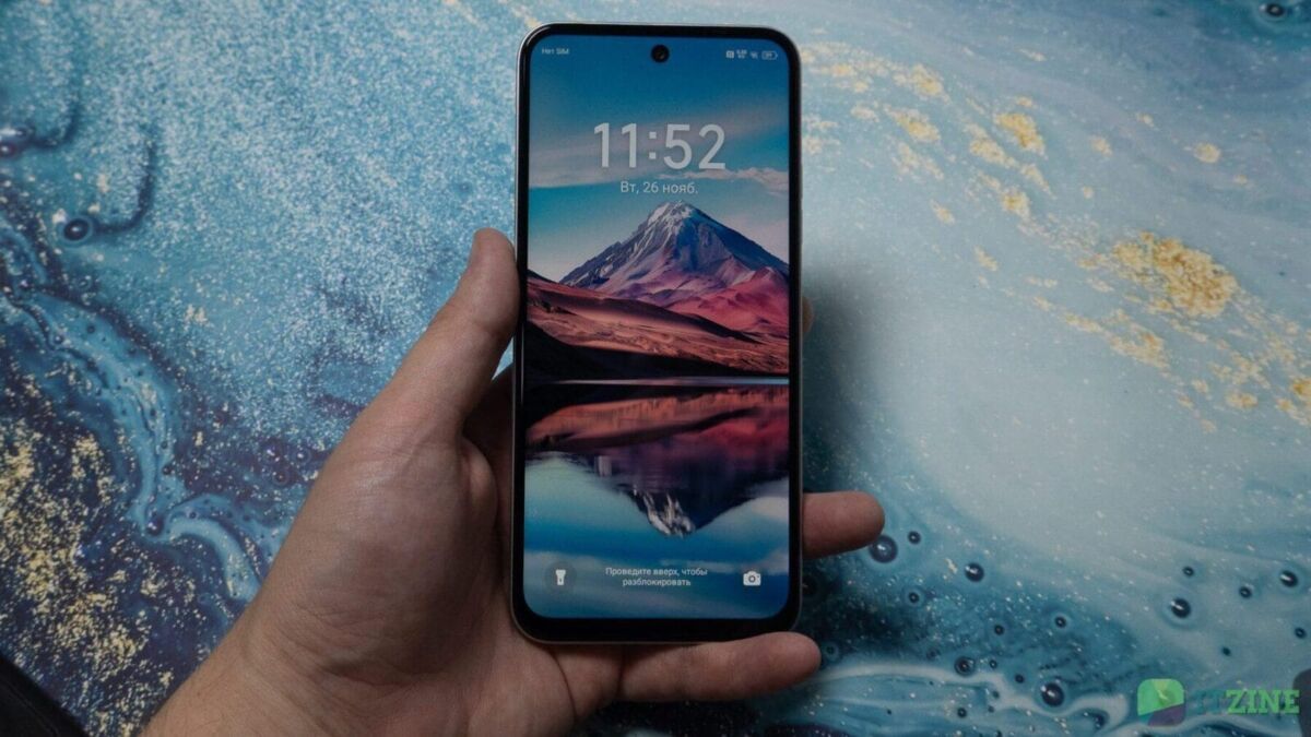 Смартфон Tecno Spark 30C в руке на фоне голубой поверхности
