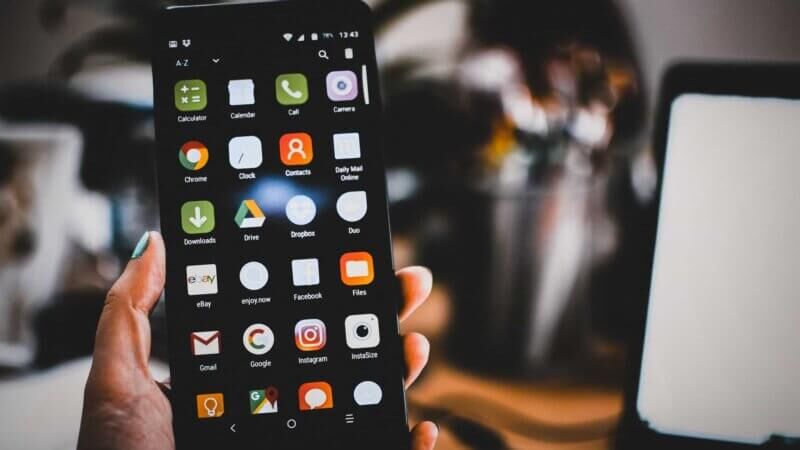 Смартфон с открытыми приложениями на экране в руке человека, крупные яркие иконки приложений