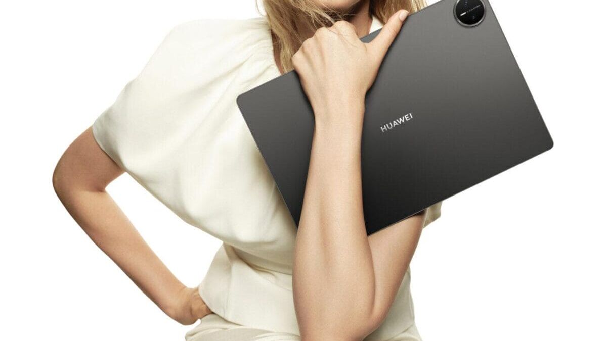 Девушка держит планшет Huawei MatePad Pro 13,2 дюйма в руке смотрит в камеру смартфом на фоне белого
