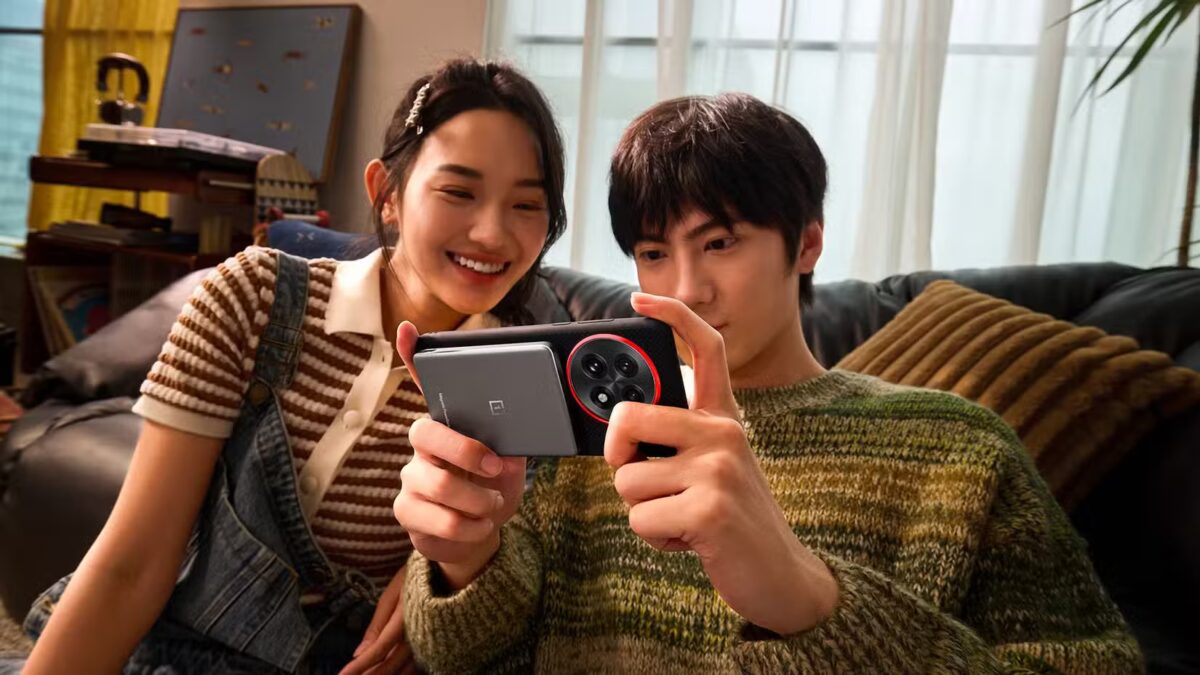 Двое улыбающихся молодых людей используют смартфон OnePlus на диване в гостиной