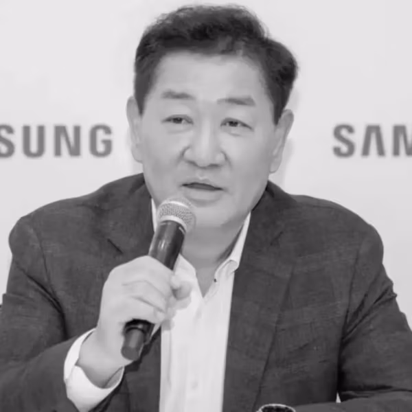 Мужчина в деловом костюме с микрофоном на фоне логотипов Samsung Electronics, Хан Джон-хи