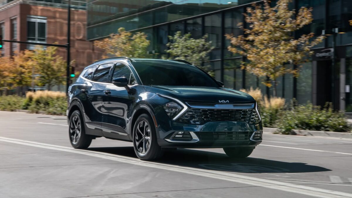Новый Kia SUV на городской улице с современными зданиями и деревьями в солнечный день
