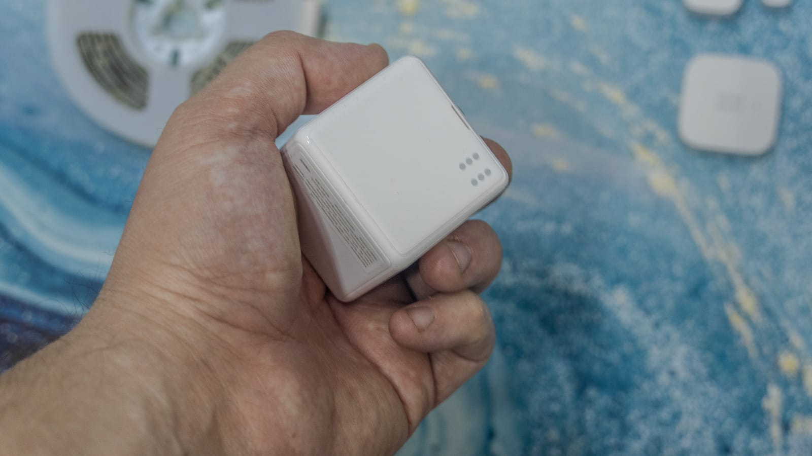 Aqara Cube T1 Pro в руке. Этот небольшой белый кубик позволяет управлять умным домом жестами – достаточно перевернуть, покрутить или встряхнуть его, чтобы запустить заранее настроенную сцену