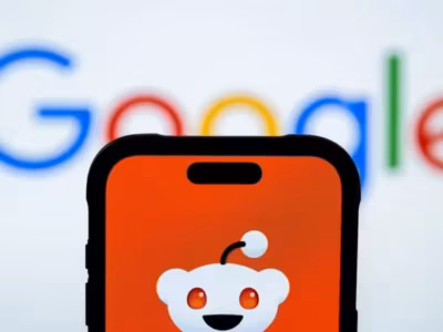 Смартфон iPhone с экраном, показывающим логотип Reddit на фоне Google
