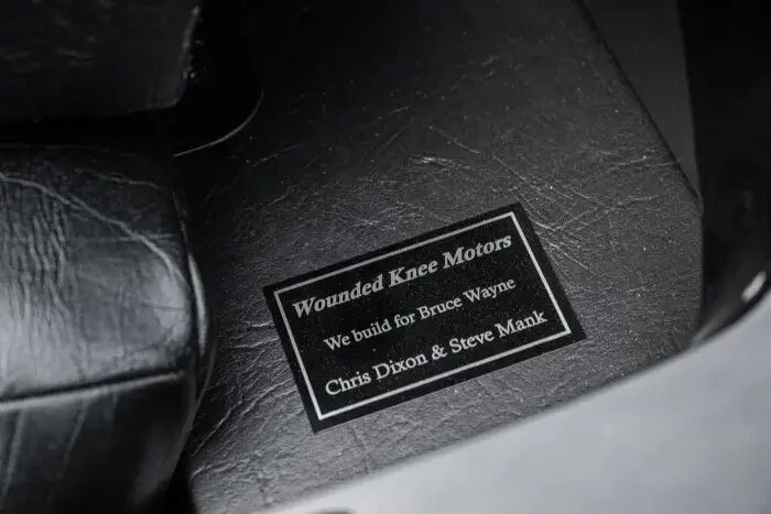 Черная табличка с надписью Wounded Knee Motors на кожаном сиденье
