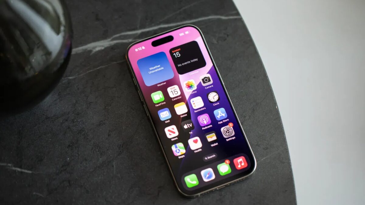 Экран iPhone 16 Pro с яркими иконками приложений и виджетом даты на темном фоне