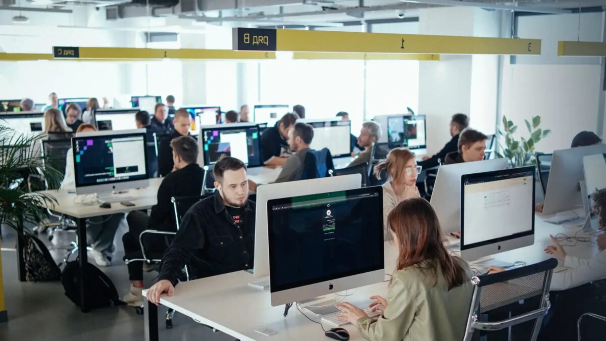 Работники в офисе используют компьютеры с экранами iMac