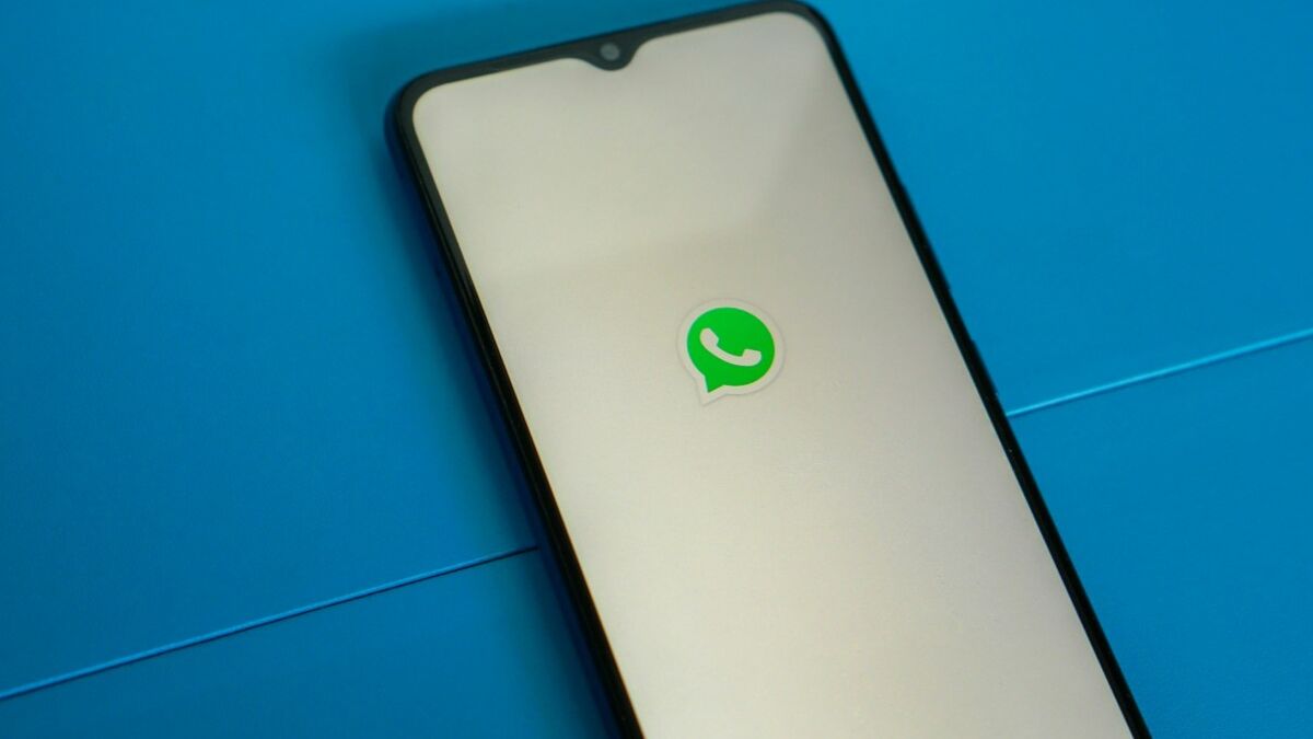 Экран смартфона с логотипом WhatsApp на голубом фоне иконки мессенджера
