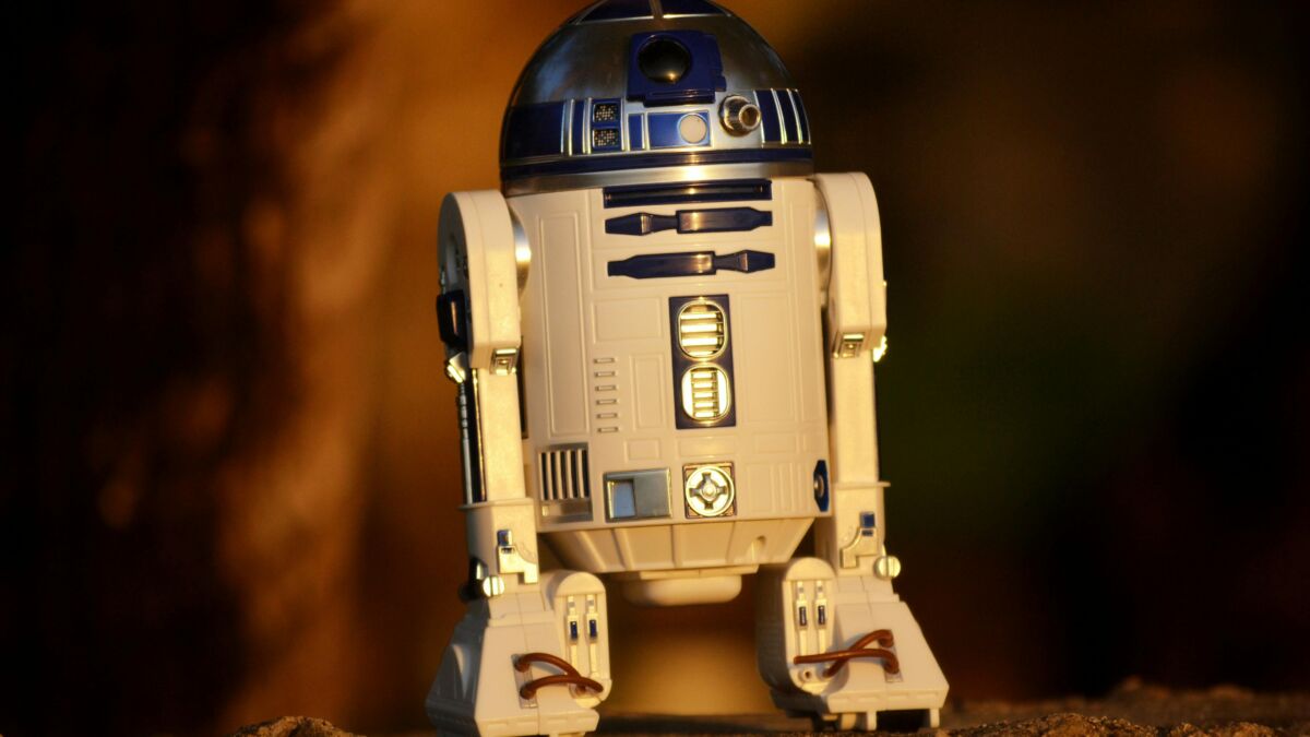 Игрушечная фигура робота R2-D2 из серии Star Wars на каменной поверхности