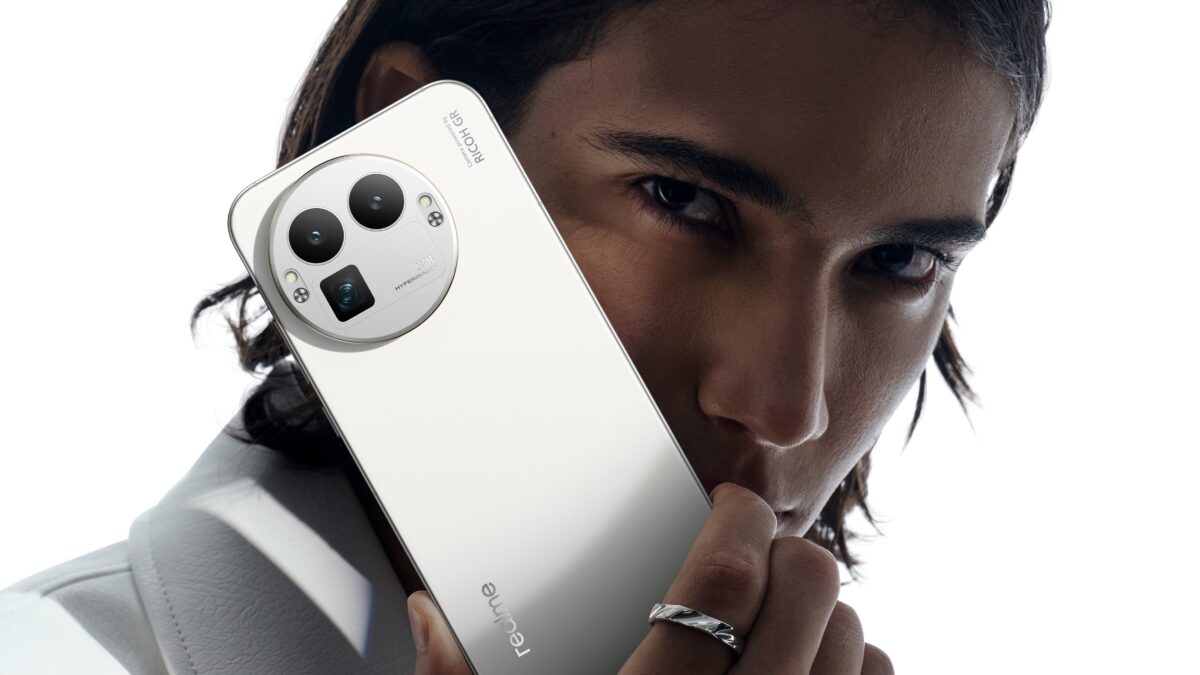 Мужчина с длинными темными волосами держит смартфон realme GT 8 Pro