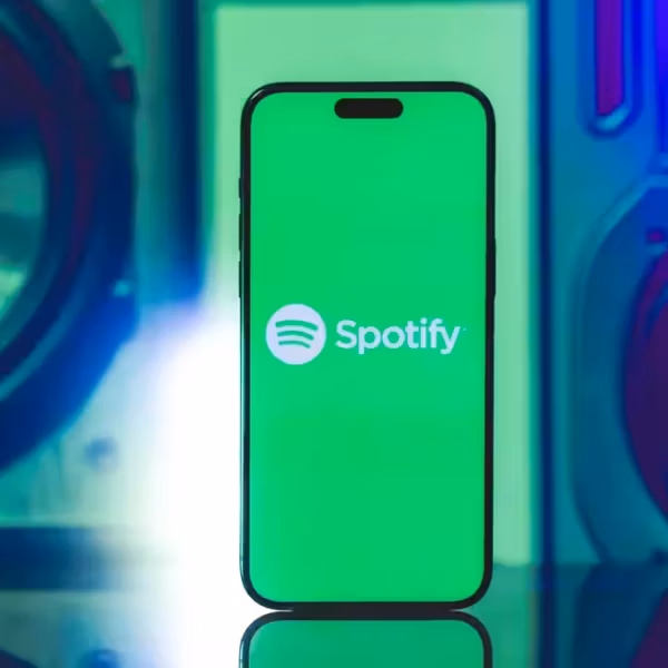 Смартфон с логотипом Spotify на экране, приложение для потоковой музыки на фоне динамиков